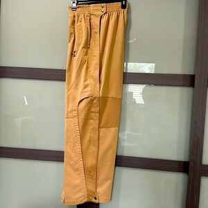 Men Tan Pants with snaps up the entire length of the pants leg.